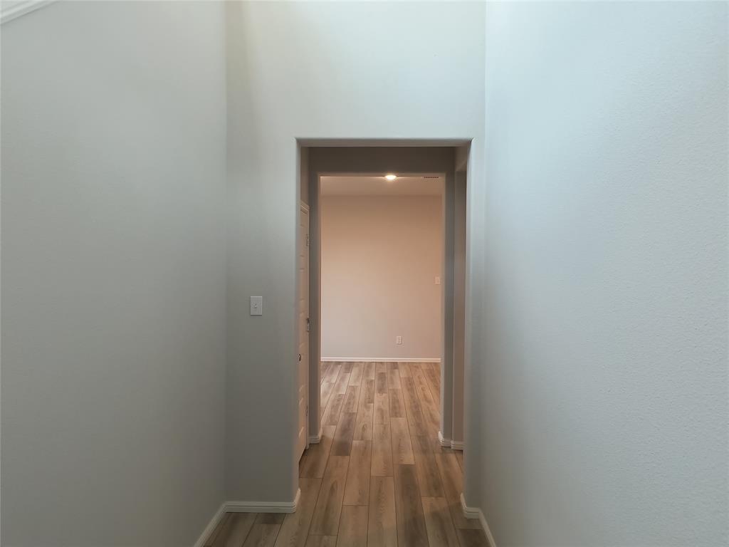 Hallway featuring wood-finish flooring, light grey painted walls, and an arched doorway Hallway featuring wood-finish flooring, light grey painted walls, and an arched doorway