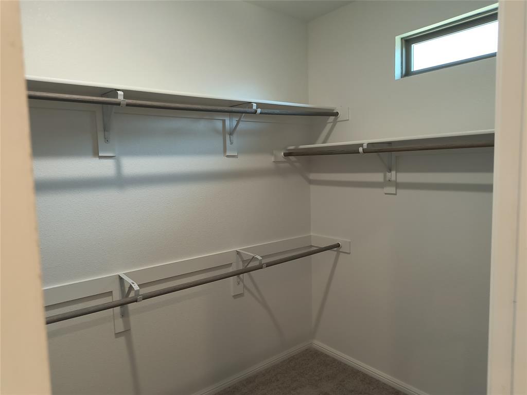 Walk-in closet featuring multiple shelving units, hanging rods, and a high-set window