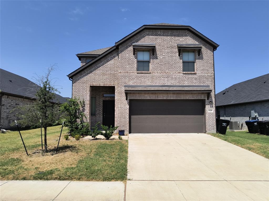 Brick exterior, attached garage, concrete driveway, covered entry, and front landscaping