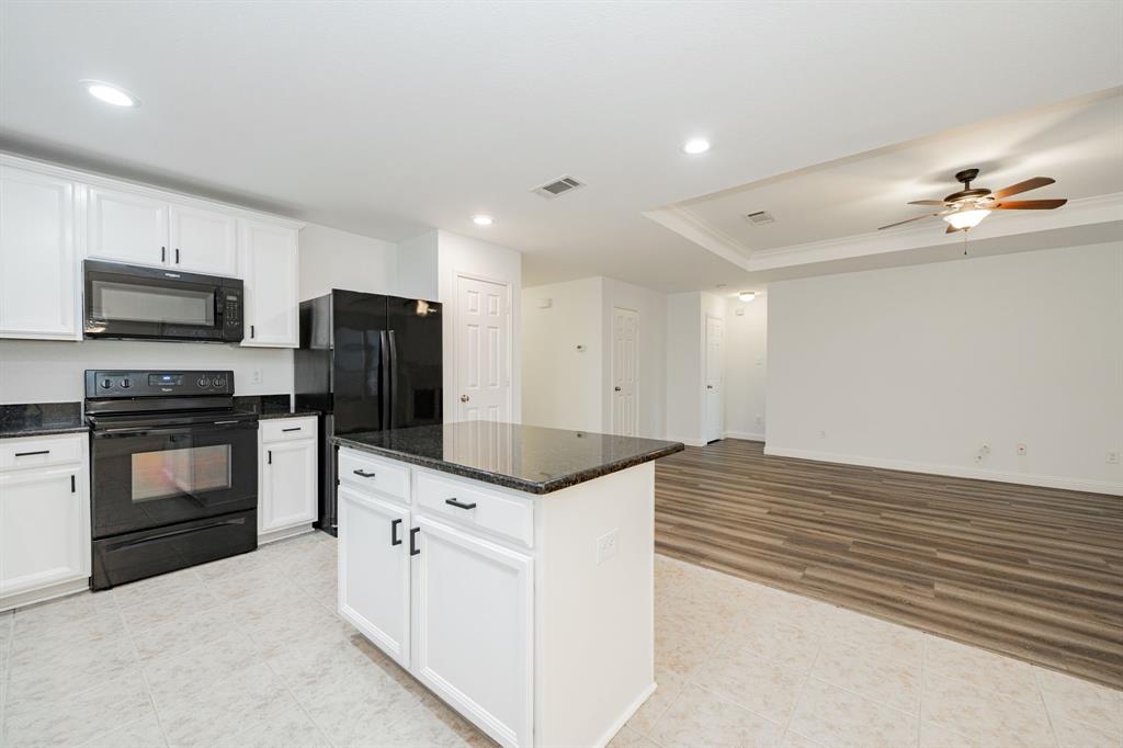 Kitchen featuring black appliances, ornamental molding, white cabinets, ceiling fan, and a raised ceiling