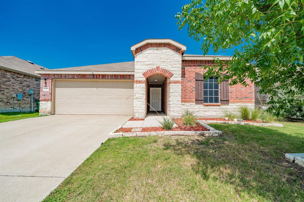 View of front of house featuring an attached garage, stone siding, concrete driveway, a front lawn, and brick siding View of front of house featuring an attached garage, stone siding, concrete driveway, a front lawn, and brick siding