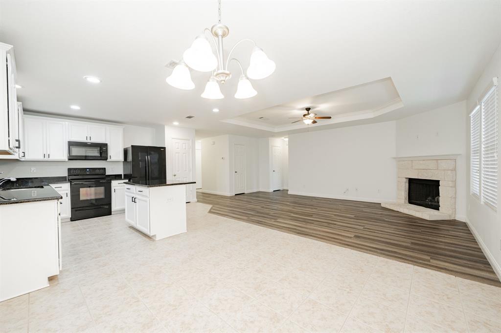 Kitchen with black appliances, dark countertops, ceiling fan, a chandelier, and crown molding