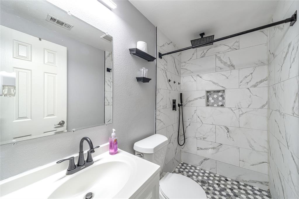 Bathroom with vanity, a marble finish shower, and a textured wall
