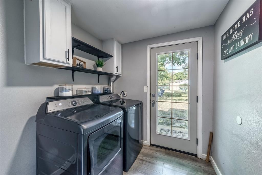 Washroom with separate washer and dryer, cabinet space, wood finished floors, and a textured wall