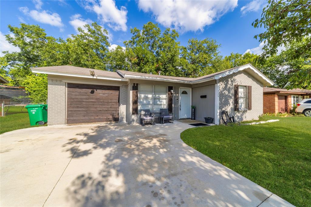 Ranch-style home featuring a garage, brick siding, and driveway