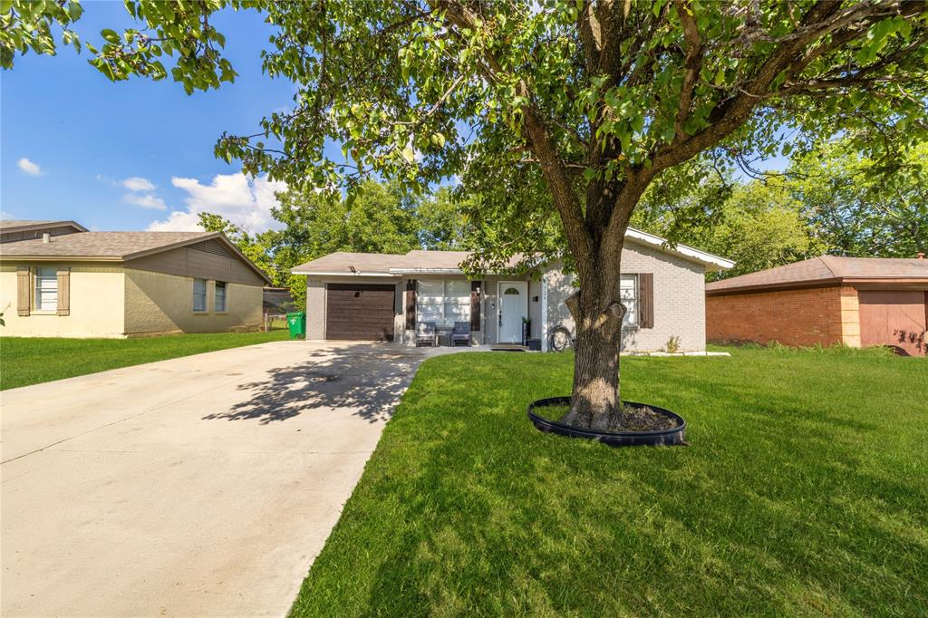 Ranch-style house with concrete driveway, a garage, and a front lawn