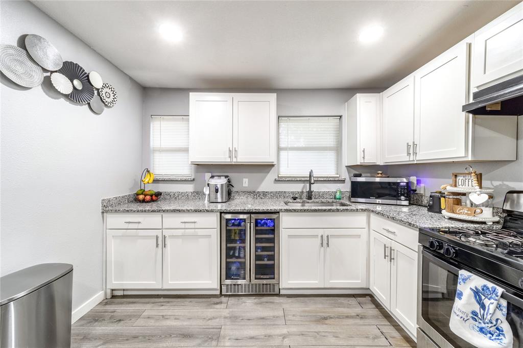 Kitchen featuring stainless steel appliances, beverage cooler, white cabinets, and recessed lighting