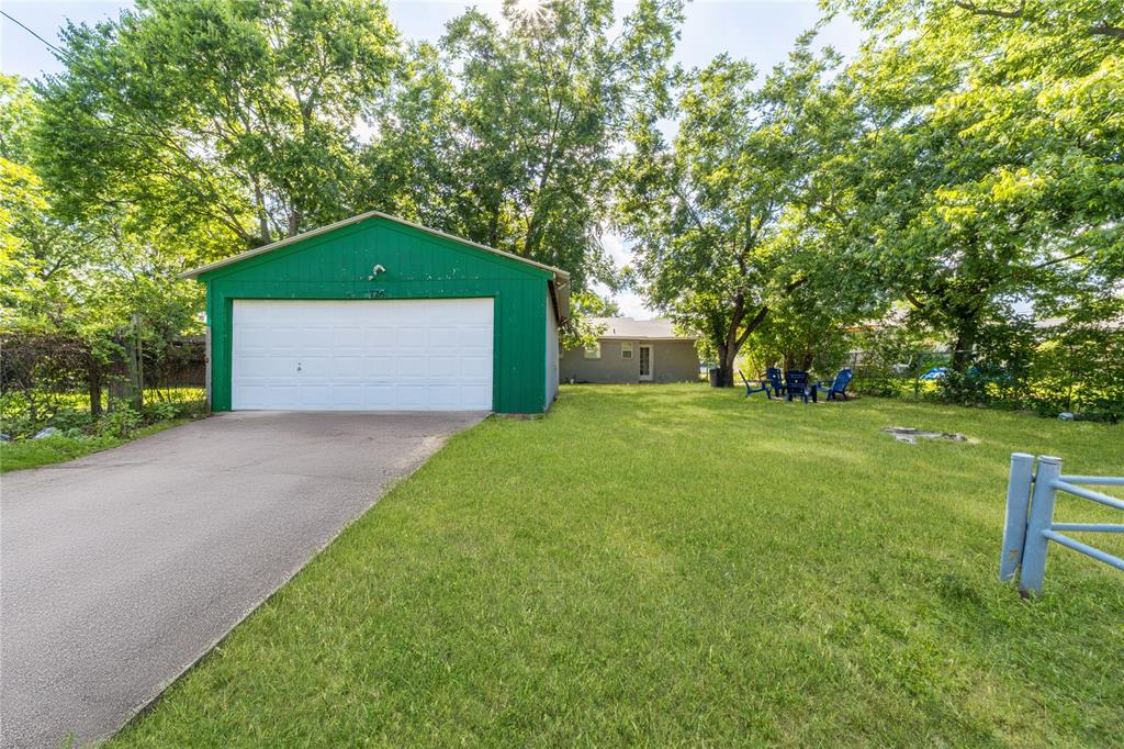 View of front of house with a front yard, concrete driveway, and view of wooded area