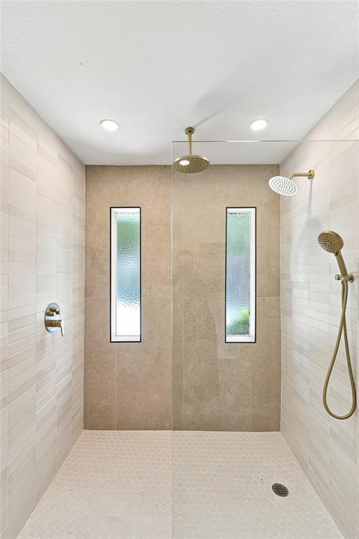 Walk-in shower with dual shower heads, recessed lighting, two vertical windows, and hexagon tile flooring