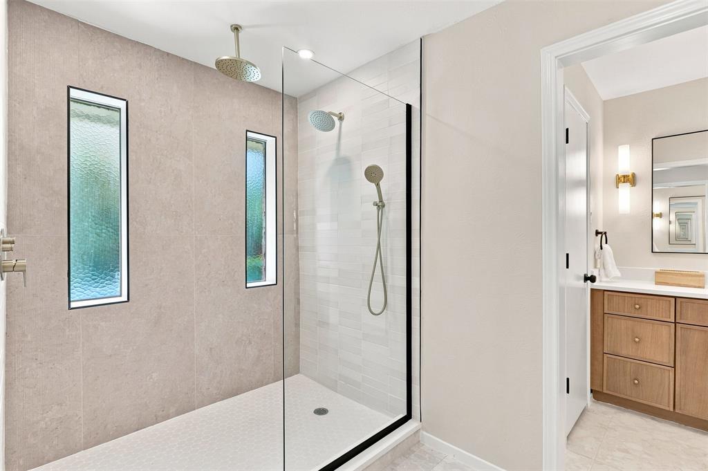 Glass-enclosed shower with a rainfall showerhead, handheld shower, and vertical accent windows