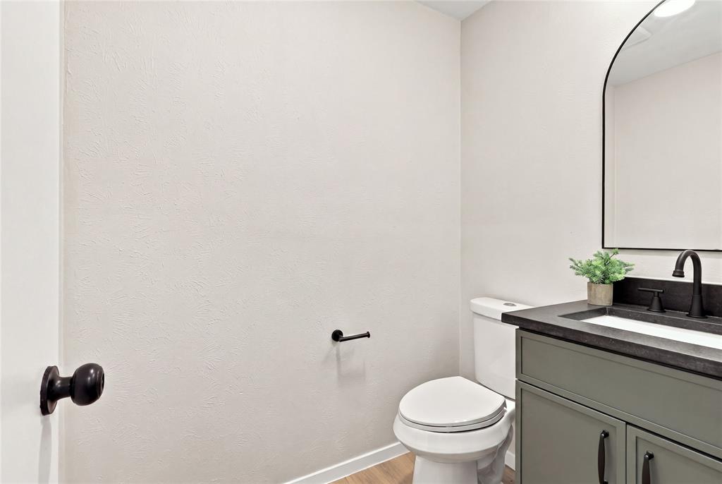 Vanity with a dark countertop, white basin, and matte black faucet