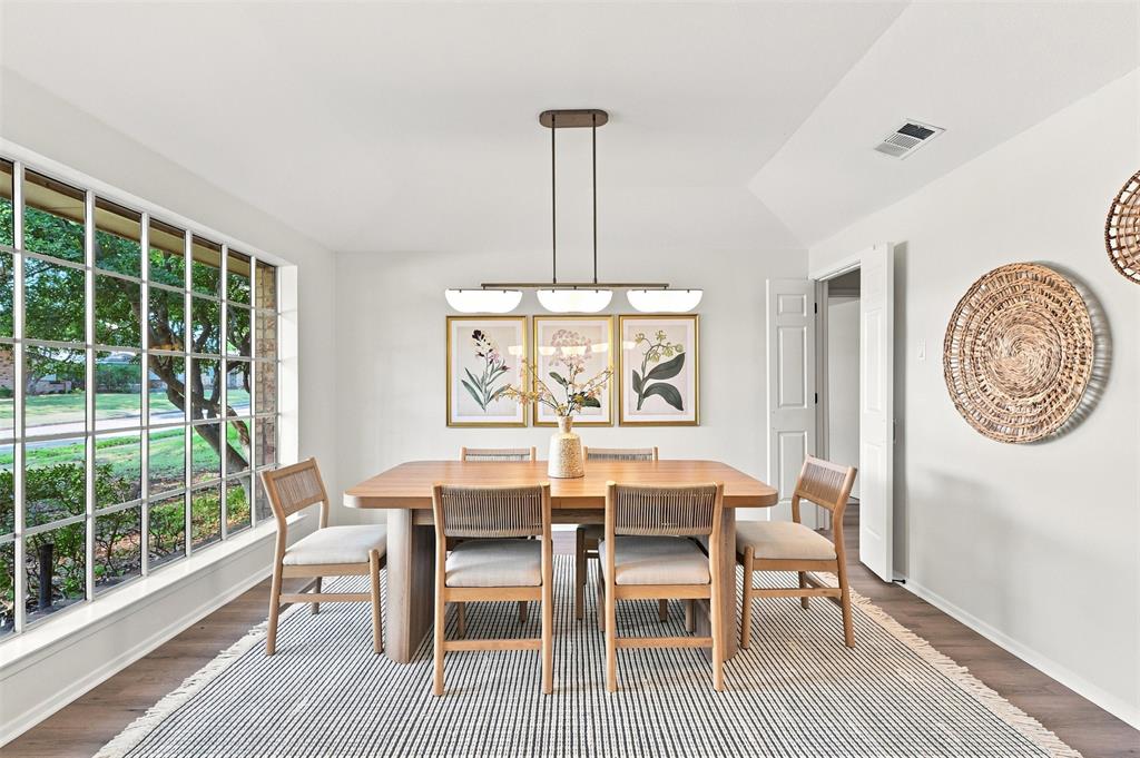 Bright dining room anchored by a wood-finish table and chairs, illuminated by a linear pendant fixture