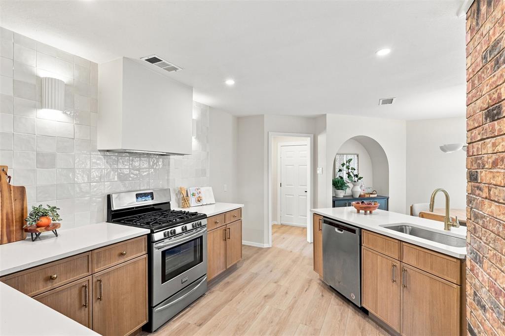 Kitchen featuring stainless steel appliances, wood-finish cabinetry, white countertops, and a full tile backsplash
