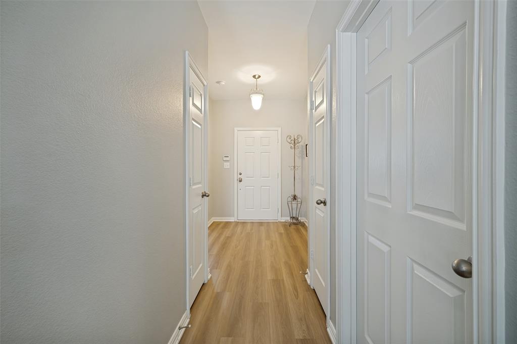 Entry hallway featuring wood-finish flooring, white paneled doors, and light gray wall paint