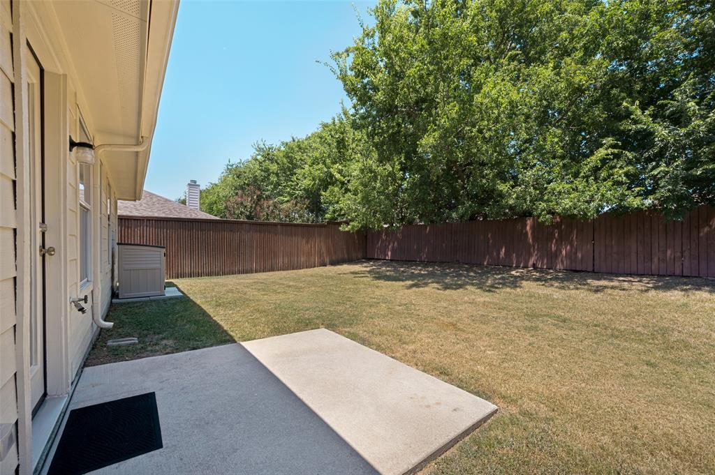 Expansive backyard with a concrete patio, wood privacy fencing, and mature trees
