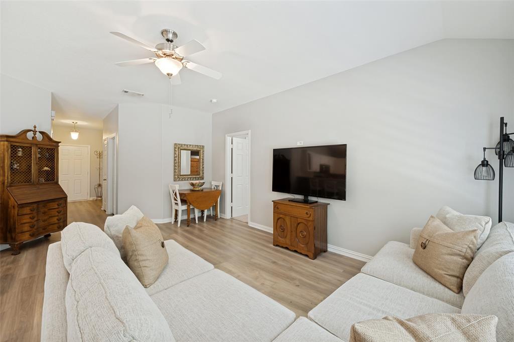 Light wood-finish flooring throughout, complemented by a ceiling fan with integrated lighting, and a vaulted ceiling