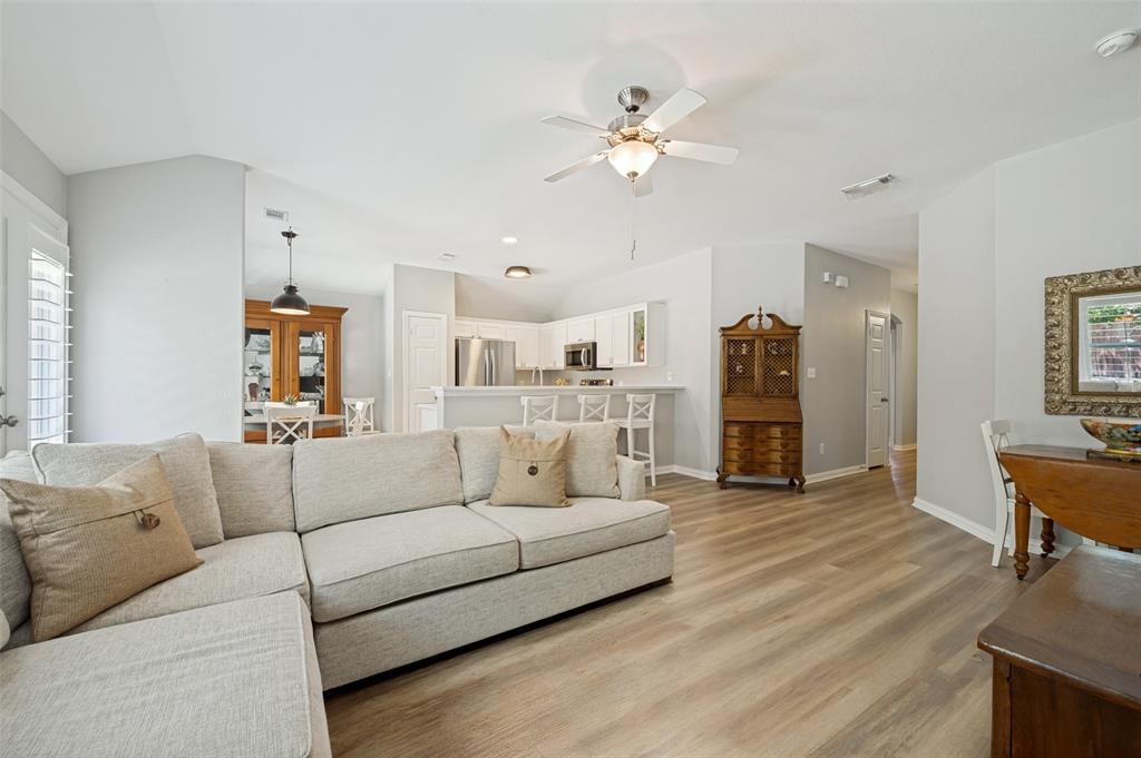 Open-concept living area featuring wood-finish flooring, vaulted ceilings, and a ceiling fan