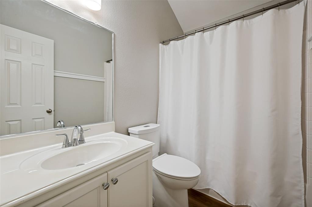 Vanity with an integrated sink and chrome faucet, white paneled door, and a toilet