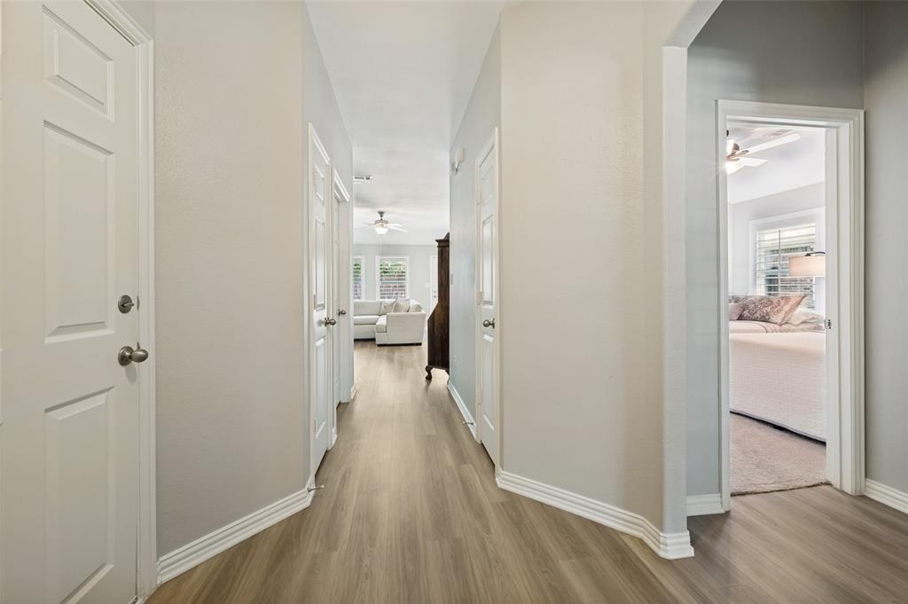 Hallway featuring wood-finish flooring, light-toned walls, and white trim