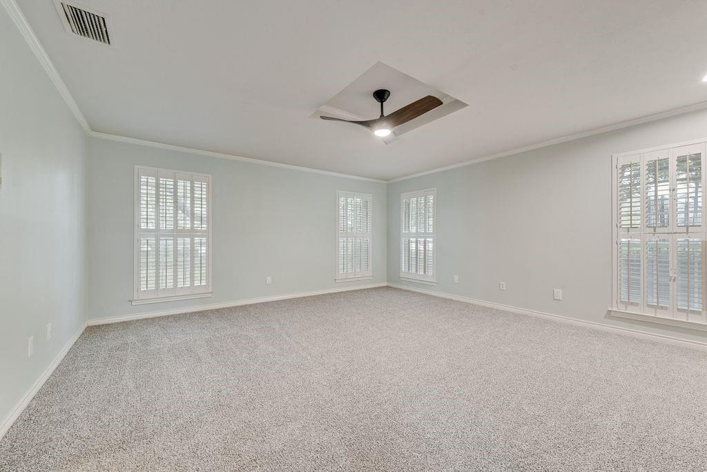 Spacious room featuring light-colored walls, crown molding, and plush carpeting