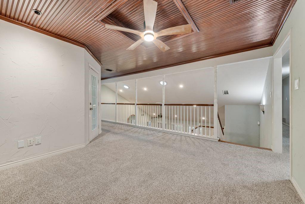 Loft area with wood-paneled ceiling, ceiling fan, carpet flooring, and white railing overlooking lower level