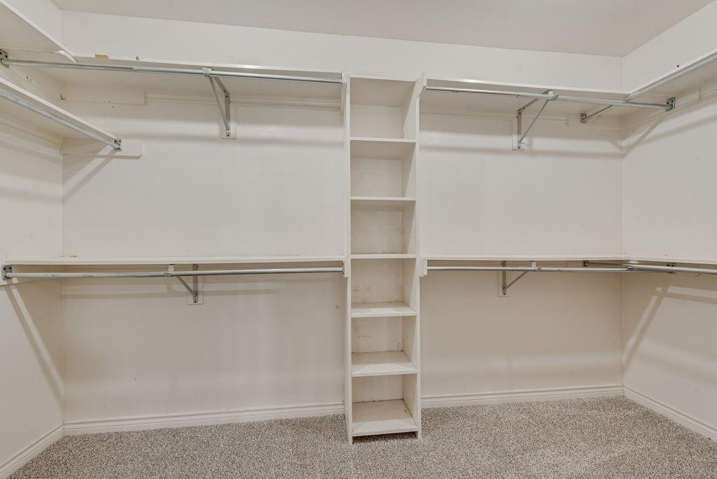 Custom closet system featuring built-in shelving, hanging rods, and light-tone carpeting