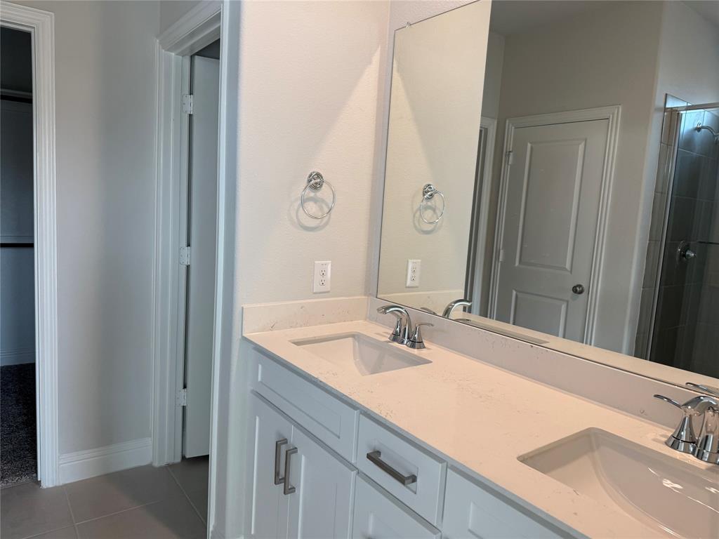 Dual vanity with white cabinetry, integrated sinks, chrome fixtures, and a large wall-mounted mirror