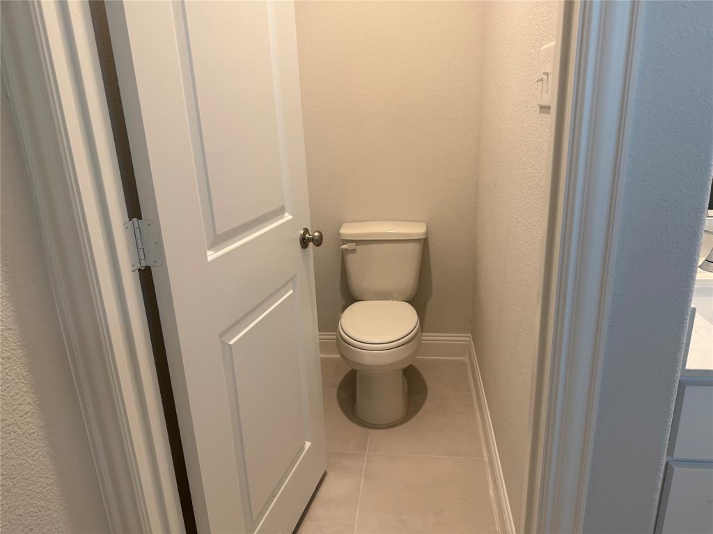 Modern toilet with a light-colored tile floor, light-toned walls, and white trim molding