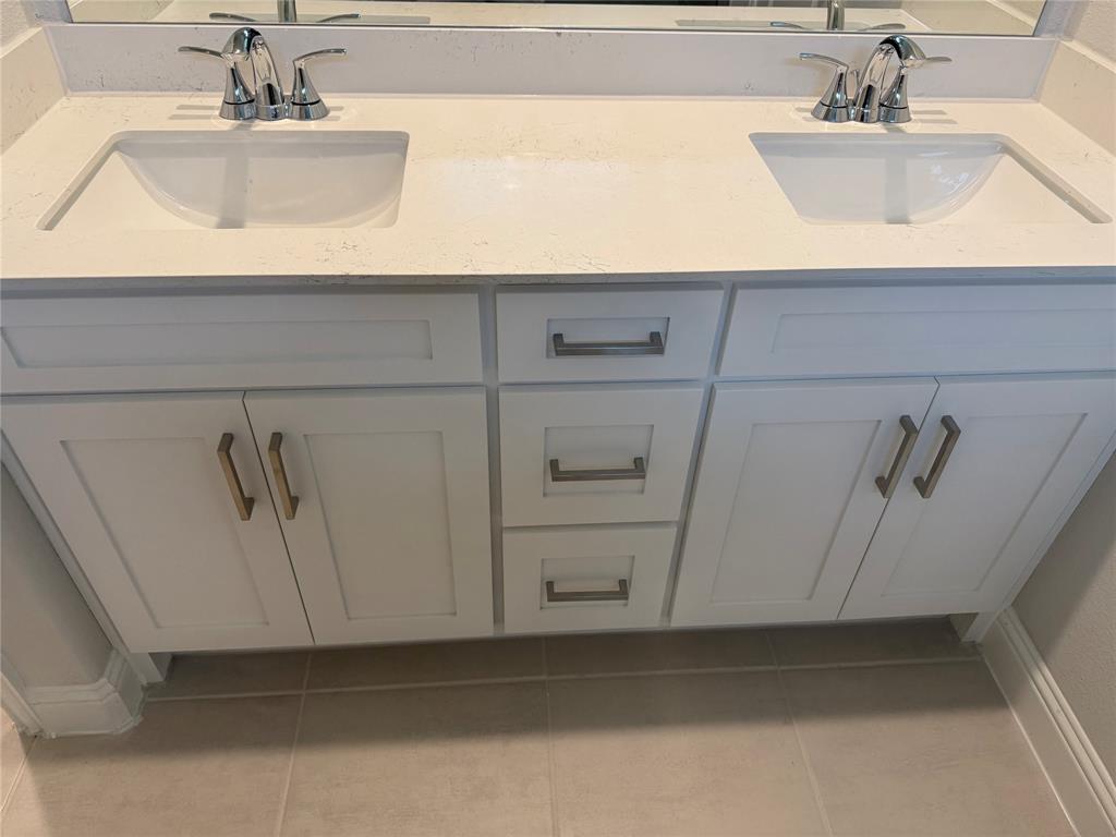 Dual vanity with integrated sinks and chrome fixtures, white cabinetry, and a light-toned countertop