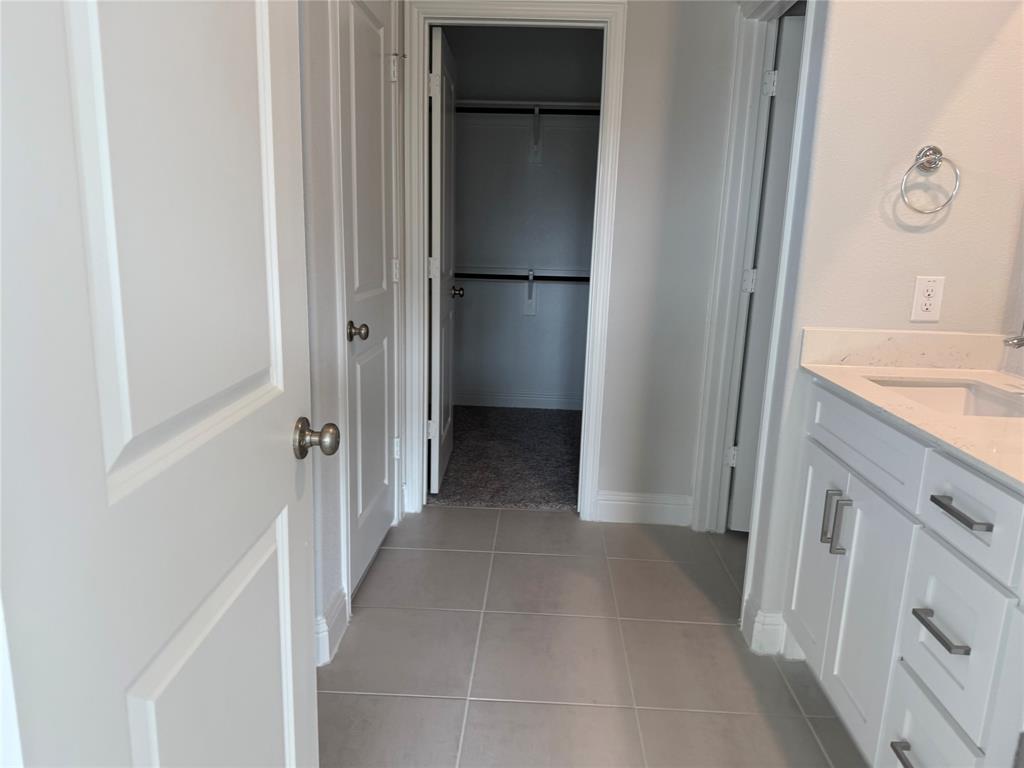 White paneled doors, light gray tile flooring, white vanity with integrated sink, light countertop, and brushed nickel hardware
