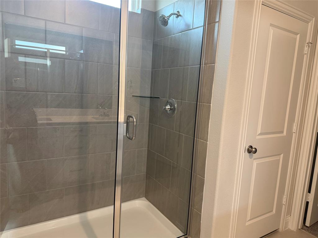 Glass-enclosed shower with subway tile surround, chrome fixtures, and a built-in shelf