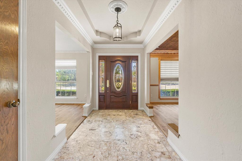 A welcoming entry featuring a beautiful front door, detailed ceiling, and marble tile flooring.