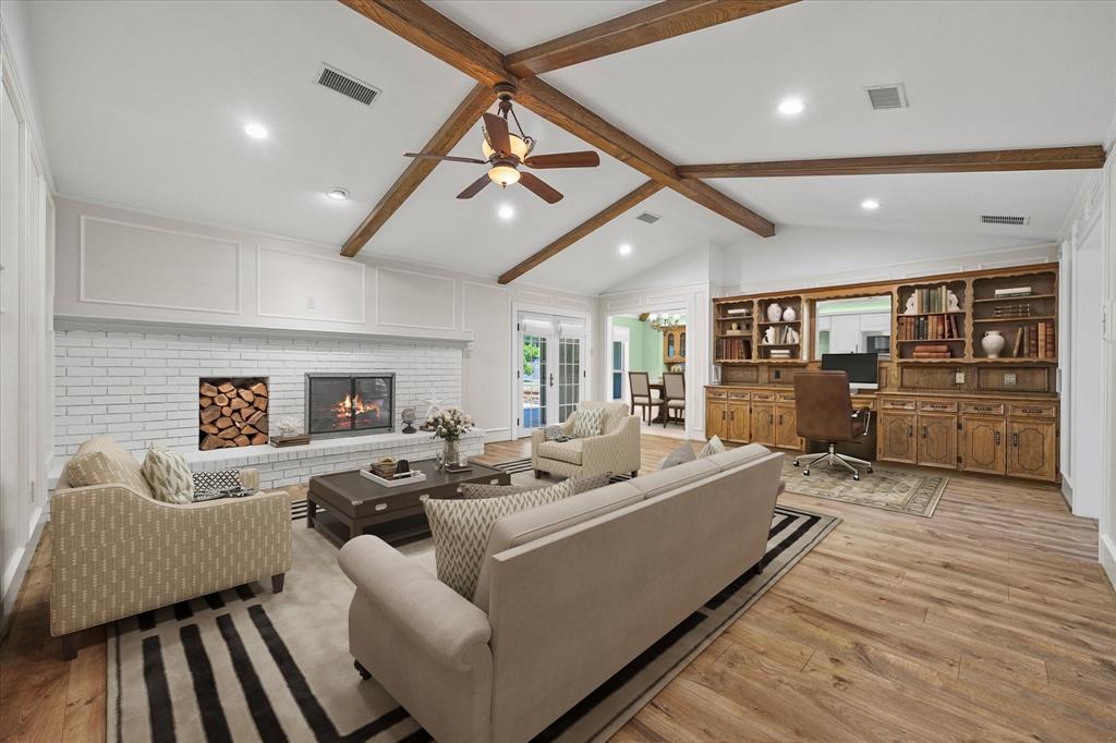 Virtually stated spacious family room featuring a dramatic vaulted ceiling with exposed beams, cozy fireplace, and beautiful built in cabinetry that contains storage and even a desk!