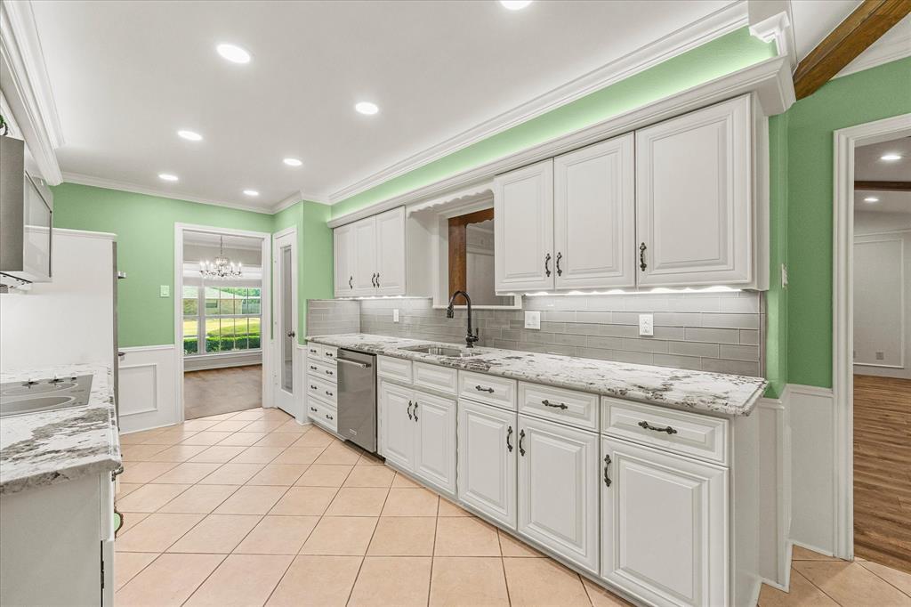 Updated kitchen with granite countertops, undercounter lighting, above-cabinet lighting, updated and abundant cabinetry, and stylish tile backsplash.