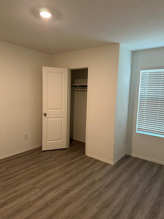 Unfurnished bedroom featuring dark wood-style floors and a closet