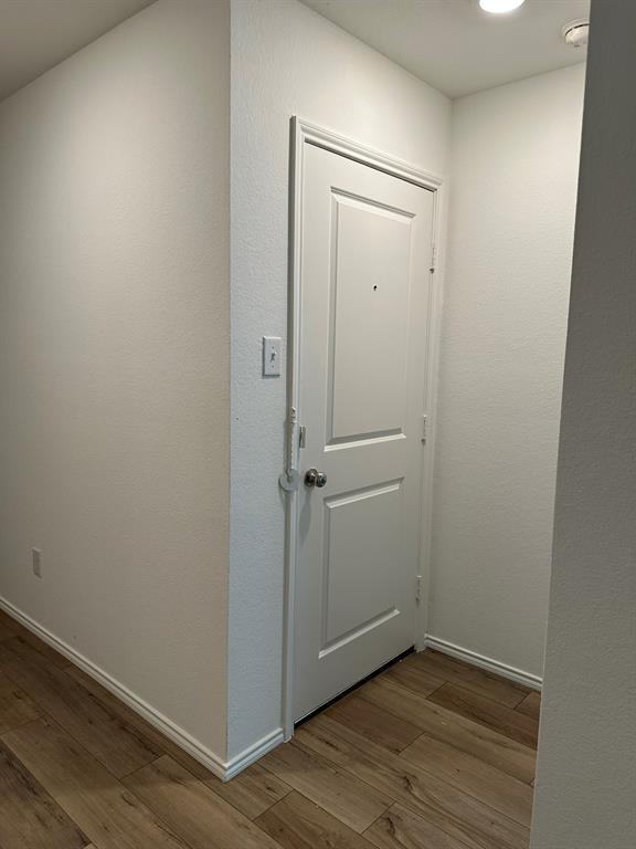 Doorway to outside featuring wood finished floors and a textured wall
