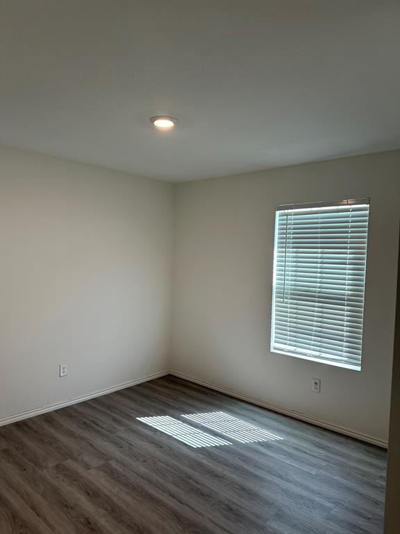 Unfurnished room with wood finished floors and baseboards