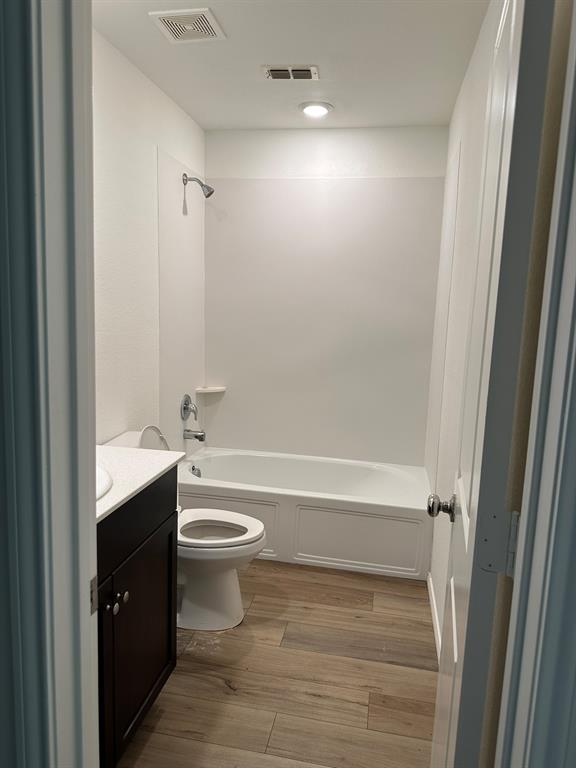 Bathroom with vanity, wood finished floors, and shower / tub combination