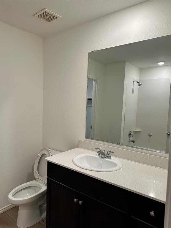 Bathroom with vanity, wood finished floors, and a shower
