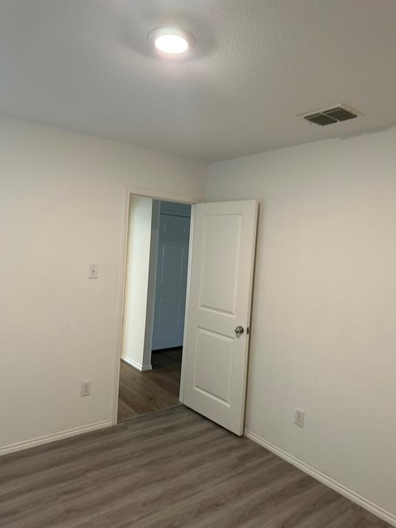 Empty room featuring wood finished floors and a textured ceiling