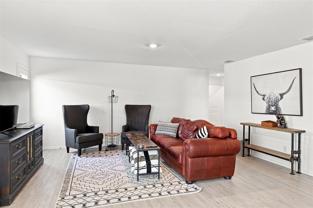 Recessed lighting illuminates the open living space, featuring light wood-finish flooring