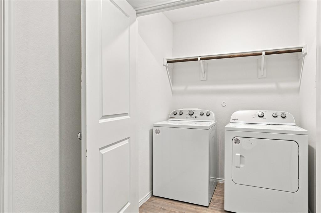 Dedicated laundry closet featuring a built-in shelf and hanging rod, with wood-finish flooring