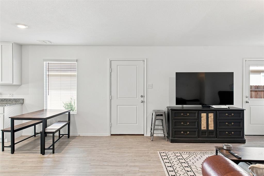 Recessed ceiling lighting, wood-finish flooring, white paneled doors, and a built-in kitchen counter with a light-toned surface