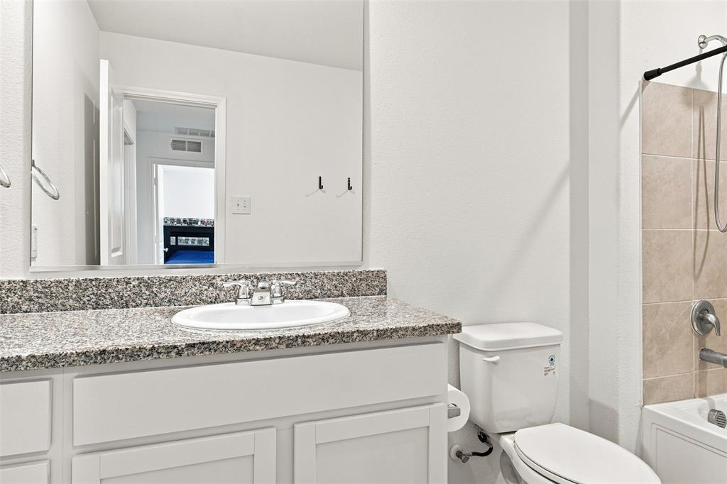 White vanity with shaker-style cabinetry, granite-finish countertop, and undermount sink
