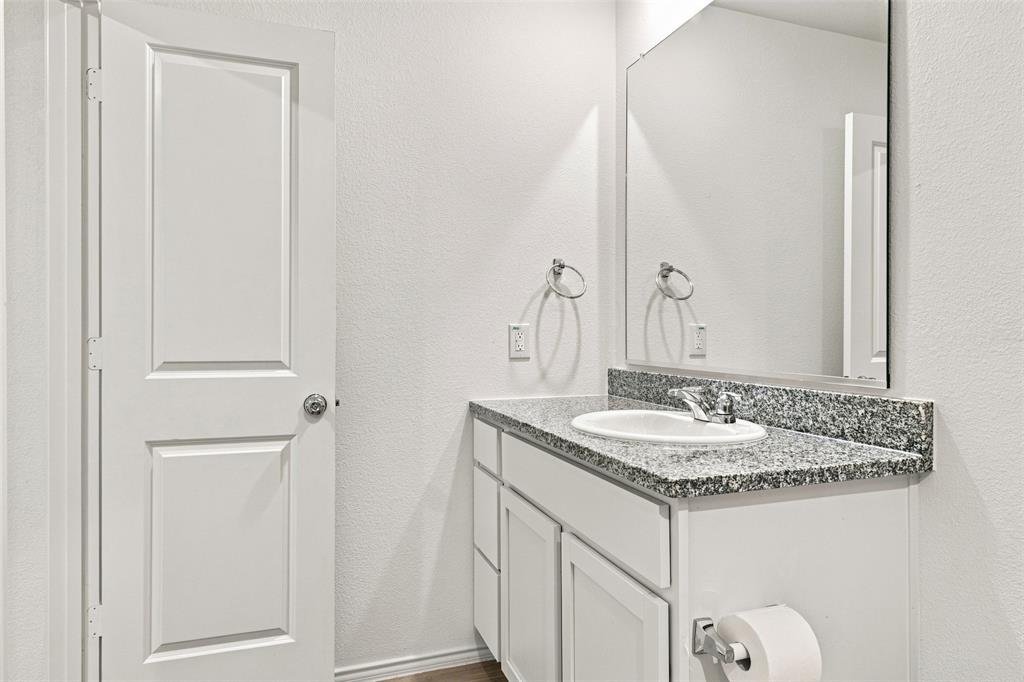 Vanity with an integrated sink, granite countertop, chrome faucet, and storage cabinetry