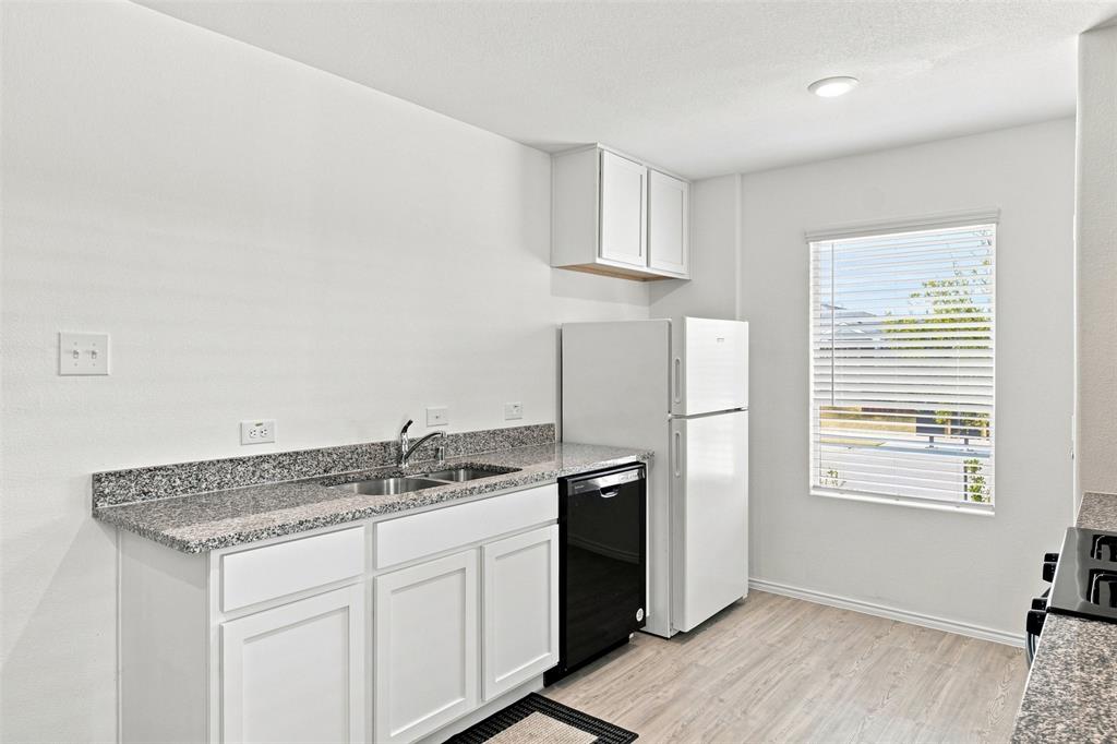 Kitchen featuring white cabinetry, speckled countertops, double basin sink, and wood-finish flooring