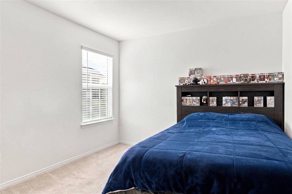 Built-in wood-finish headboard with integrated shelving, single window with blinds, and neutral carpeting