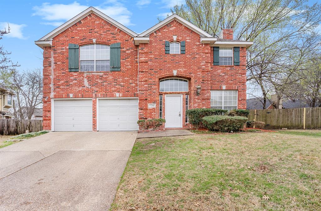 View of property featuring a garage and a front lawn View of property featuring a garage and a front lawn