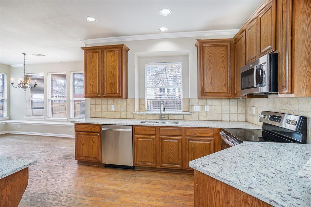Kitchen featuring light hardwood / wood-style flooring, tasteful backsplash, an inviting chandelier, sink, and appliances with stainless steel finishes