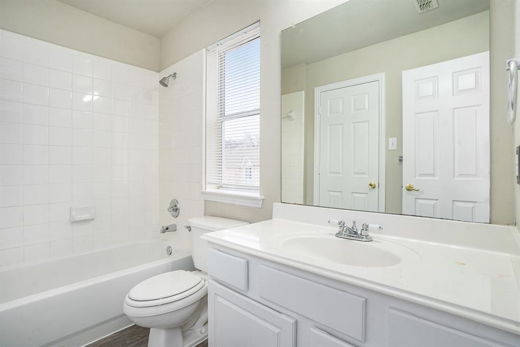 Full bathroom featuring a healthy amount of sunlight, vanity, toilet, and tiled shower / bath combo